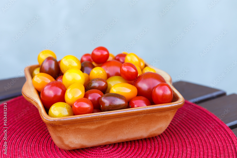 Various of colorful cherry tomatoes in a ceramic bowl. Healthy eating or vegetarian concept.