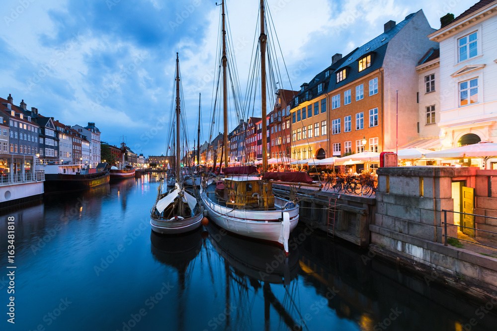 Copenhagen Nyhavn district at blue hour with wooden ships, restaurants