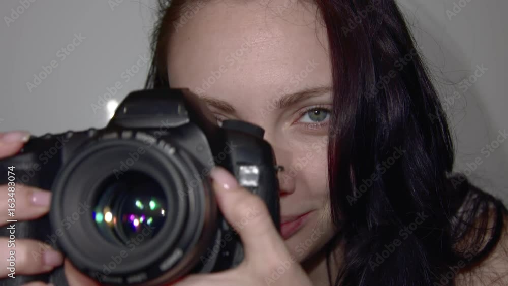 Young photographer works in the Studio. A woman takes the Picture on the camera. The camera is in the process of close-up shooting. Shutter release in slow motion. Young photographer works in the Studio. A woman takes the Picture on the camera. The camera is in the process of close-up shooting. Shutter release in slow motion.