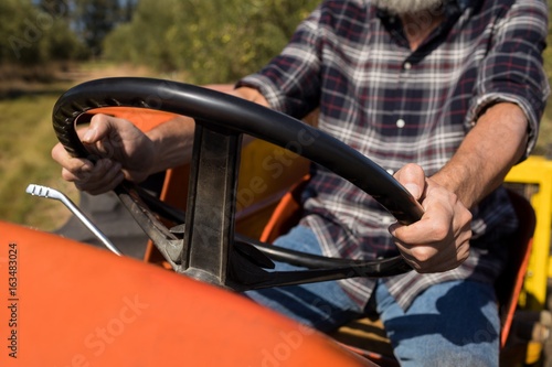 Mid section of man driving tractor in olive farm