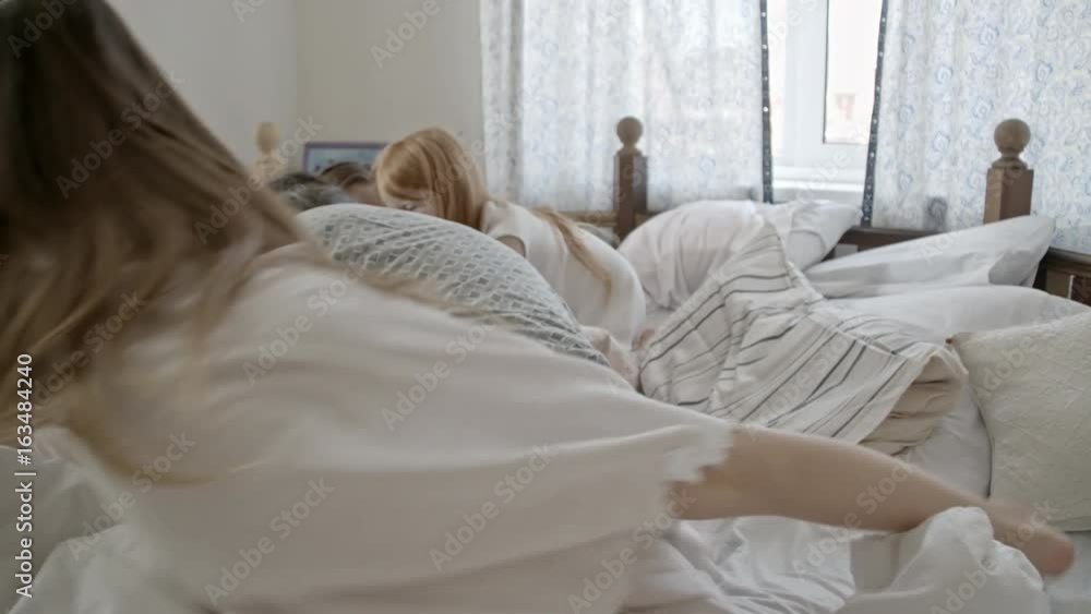 PAN with slow motion of young mother and senior father tickling and hugging little boy lying in their bed while his older sisters laughing and playing PAN with slow motion of young mother and senior father tickling and hugging little boy lying in their bed while his older sisters laughing and playing