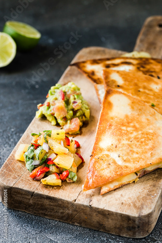 Grilled quesadillas (tortillas) with salsa, guacamole. Dark background.