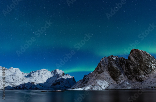 Starry sky with northern lights ofer steep rocky mountains in northern Norway