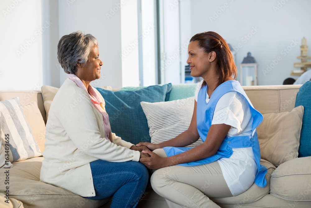 Obraz premium Female doctor comforting senior woman in living room