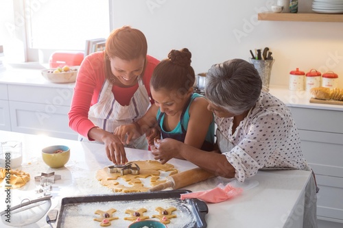 Happy multi-generation family preparing gingerbread in kitchen