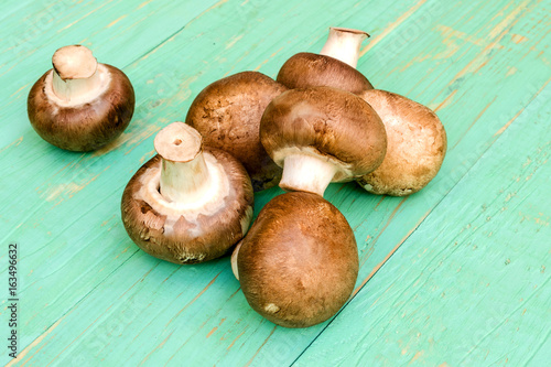 Mushrooms сhampignon lie in a heap on a blue wooden background.
