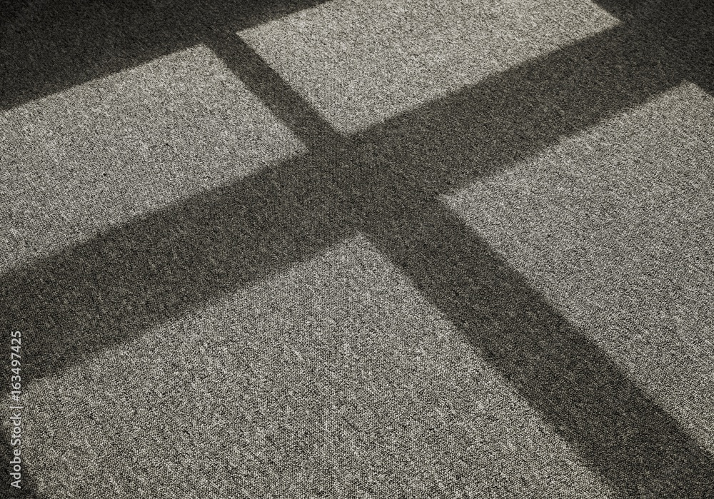 Schatten durch einfallendes Licht auf einem Teppichboden vor einem Fenster