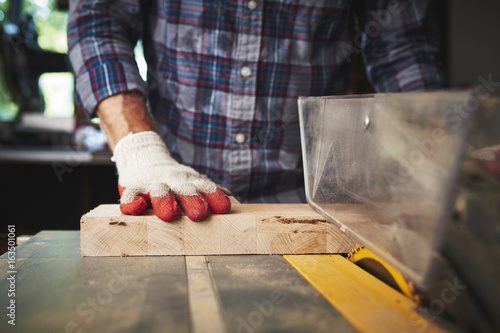 Fotografija a person cutting wood with a table saw