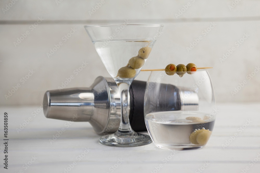 Green olives in vodka martini with cocktail shaker Green olives in vodka martini with cocktail shaker