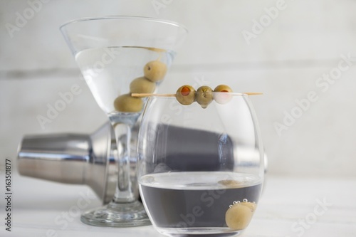 Close up of green olives in vodka martini with cocktail shaker