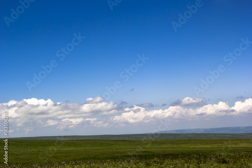 Foto Летний пейзаж. Белые облака на синем небе над зеленой долиной