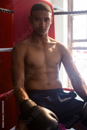 Portrait of confident man sitting in boxing ring © wavebreak3