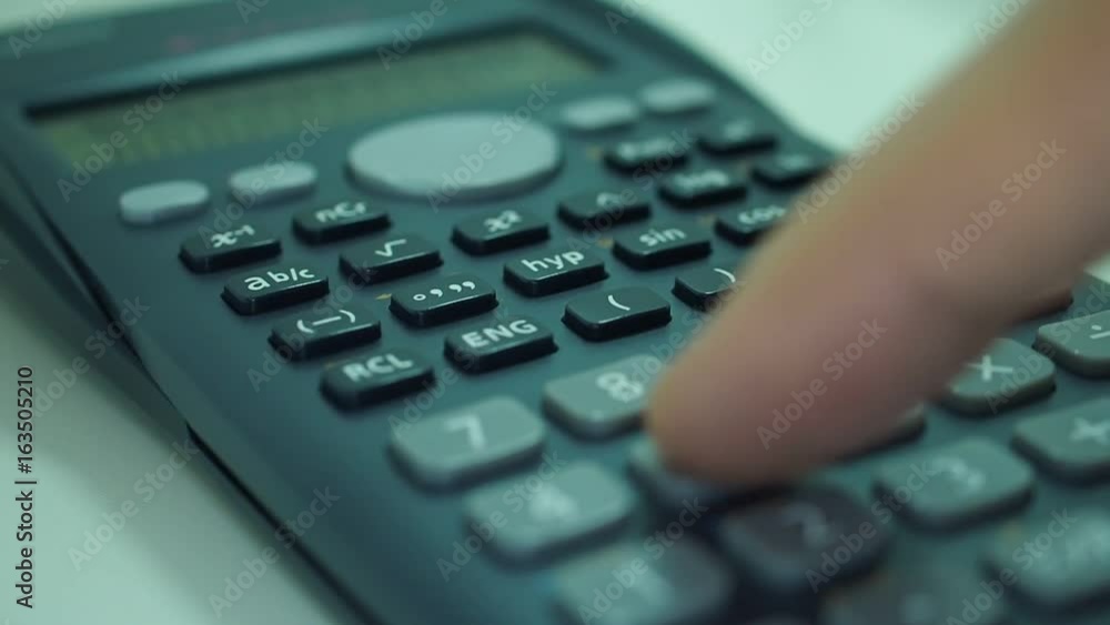 Finger presses the engineering calculator buttons. Closeup shot Finger presses the engineering calculator buttons. Closeup shot