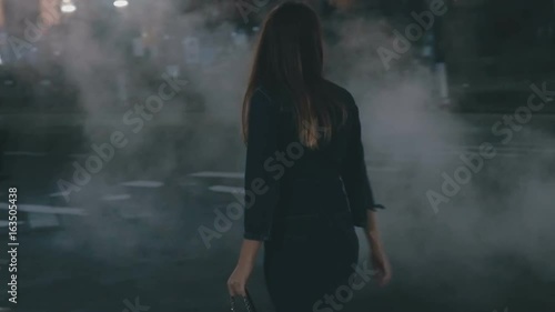 Girl is walking along the road and looking at the steam slow motion photo