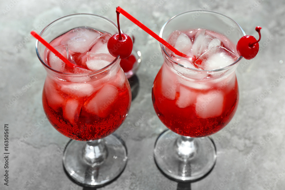 Tequila cocktails in glasses with ice and straws on grey background Tequila cocktails in glasses with ice and straws on grey background