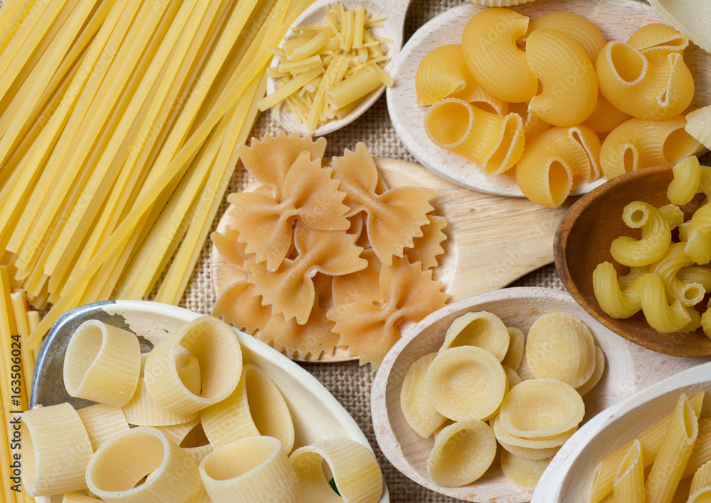 composition of raw Italian pasta in wooden spoons 