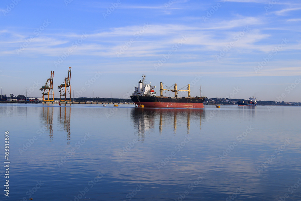 Gorgeous landscape of port of Huelva with cargo ships, Chemical and cranes, with reflections in a sea in calm