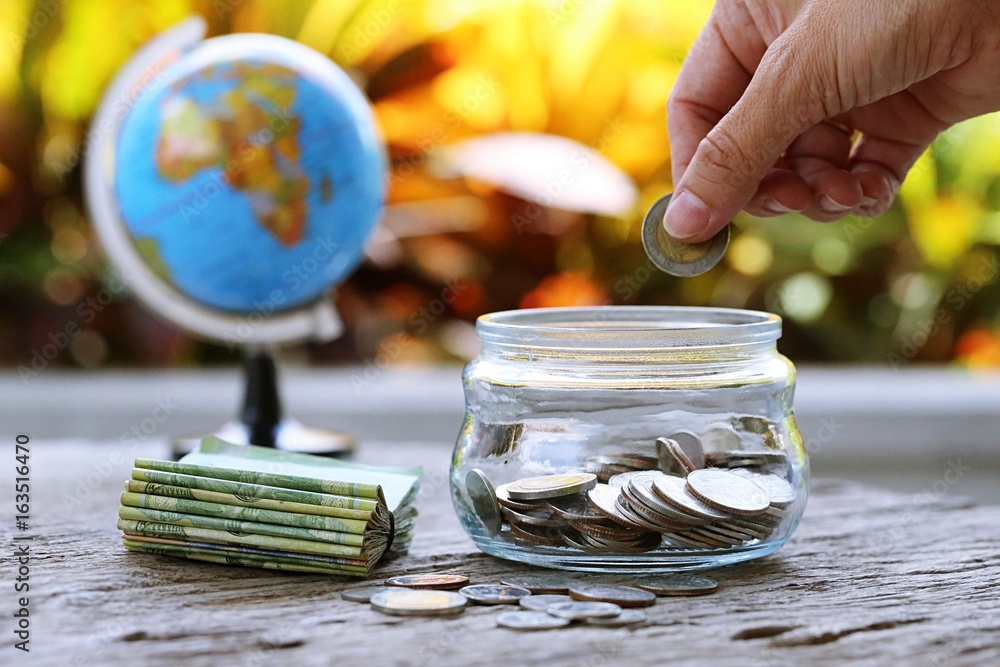 World globe map and money bank on table closeup garden leaf blur background. Concept of financial money saving
