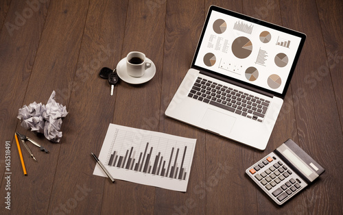 Pie chart graph icons on laptop screen with office accessories