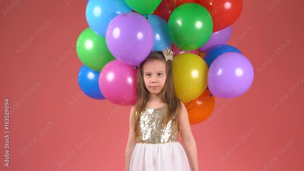Child with colorful balloons. Little girl winks and smiles. slow motion Child with colorful balloons. Little girl winks and smiles. slow motion