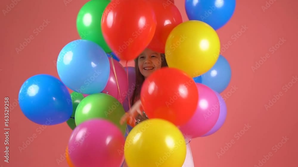 Child with colorful balloons. Little girl winks and smiles. slow motion Child with colorful balloons. Little girl winks and smiles. slow motion