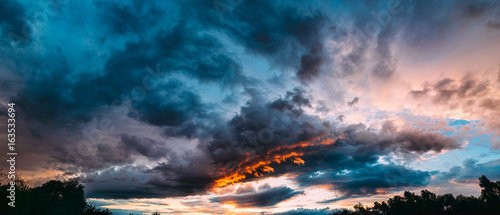 Panorama of dramatic colored blue, gray and orange sunset on beautiful sky. Sky background on sunset with clouds