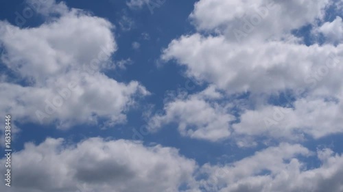 Beautiful white and grey cumulus clouds move diagonally on background of blue sky