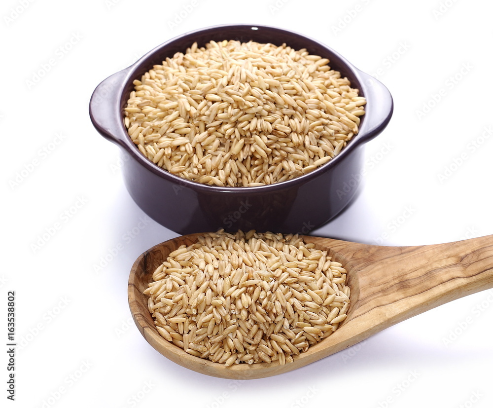 Oat grains in wooden spoon and purple porcelain cup, dish isolated on white background Oat grains in wooden spoon and purple porcelain cup, dish isolated on white background