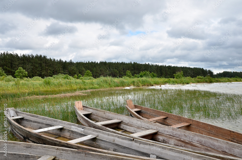 Old rustic wooden fishing boats on the lake at stormy weather, close up Old rustic wooden fishing boats on the lake at stormy weather, close up