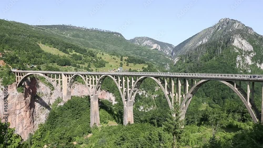 Tara canyon bridge Durdevica above Tara river Montenegro. Cars drive by bridge Tara canyon. Strong winde. Locked down shot. Tara canyon bridge Durdevica above Tara river Montenegro. Cars drive by bridge Tara canyon. Strong winde. Locked down shot.