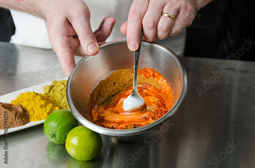 fresh organic tandoori spice ingredient mix, being blended and mixed in a metal bowl in preparation for a marinade.