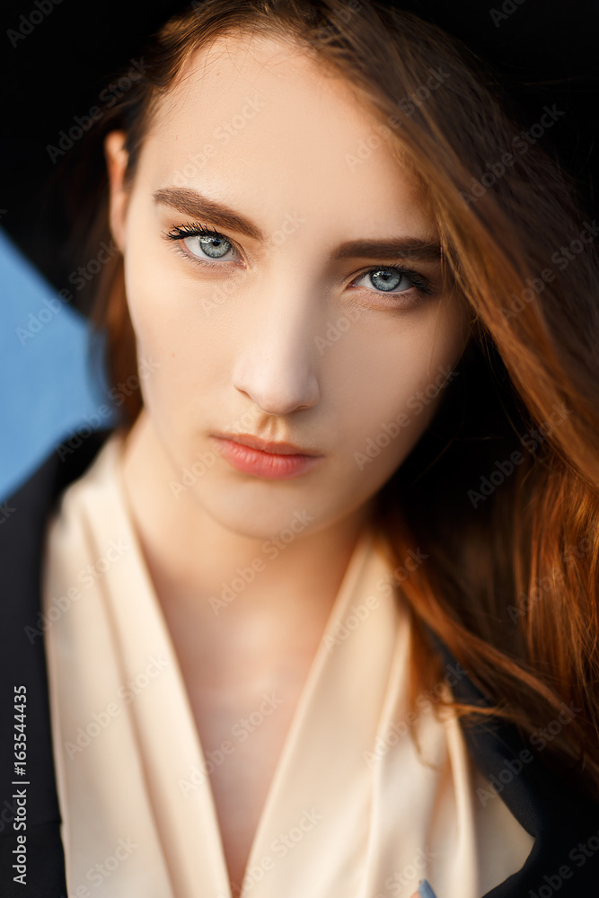 Beautiful red-haired model in a black hat