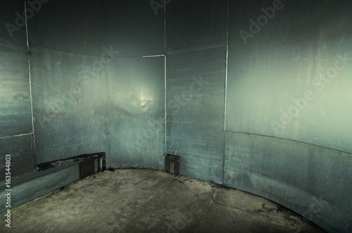 A scary cold futuristic metal sheet prison cell, with a harsh concrete floor. An aqua green empty metal prison cell perfect for compositing.