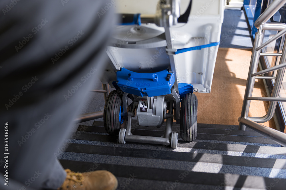 london, england, 02/02/2017 A man in an industrial warehouse lifting heavy items up stairs with a small industrial stair walking lifting style device. london, england, 02/02/2017 A man in an industrial warehouse lifting heavy items up stairs with a small industrial stair walking lifting style device.