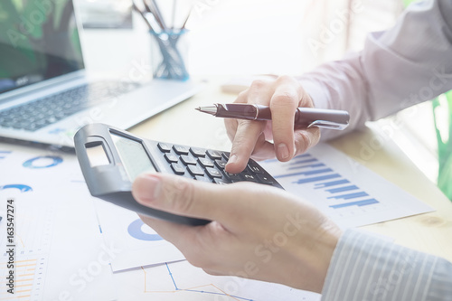 Close up young Asian Business man using a calculator to calculate the numbers.Business finances and accounting concept