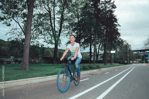 A man is riding a bicycle in a park on the waterfront