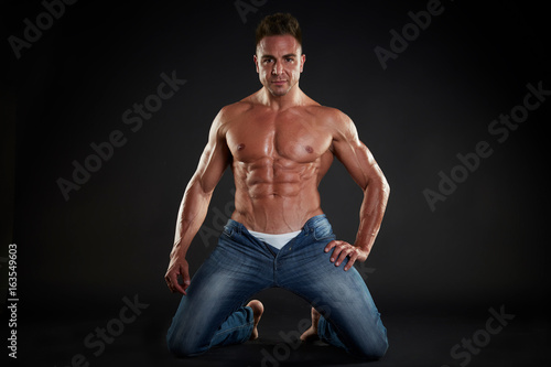 Handsome muscular fit young man on studio background 