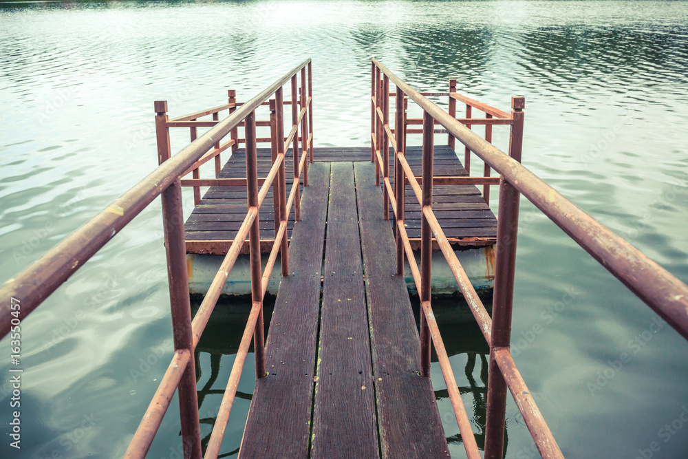 Old wooden and steel made jetty floating on the lakeside.