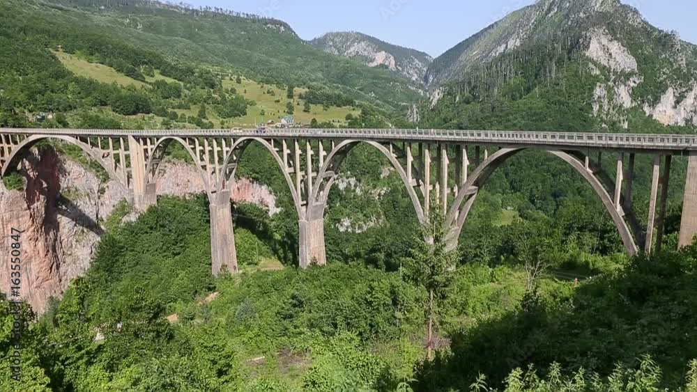 Tara canyon bridge Durdevica above Tara river Montenegro. Slow motion shot cars drive by bridge Tara canyon. Strong winde. Locked down shot. Tara canyon bridge Durdevica above Tara river Montenegro. Slow motion shot cars drive by bridge Tara canyon. Strong winde. Locked down shot.