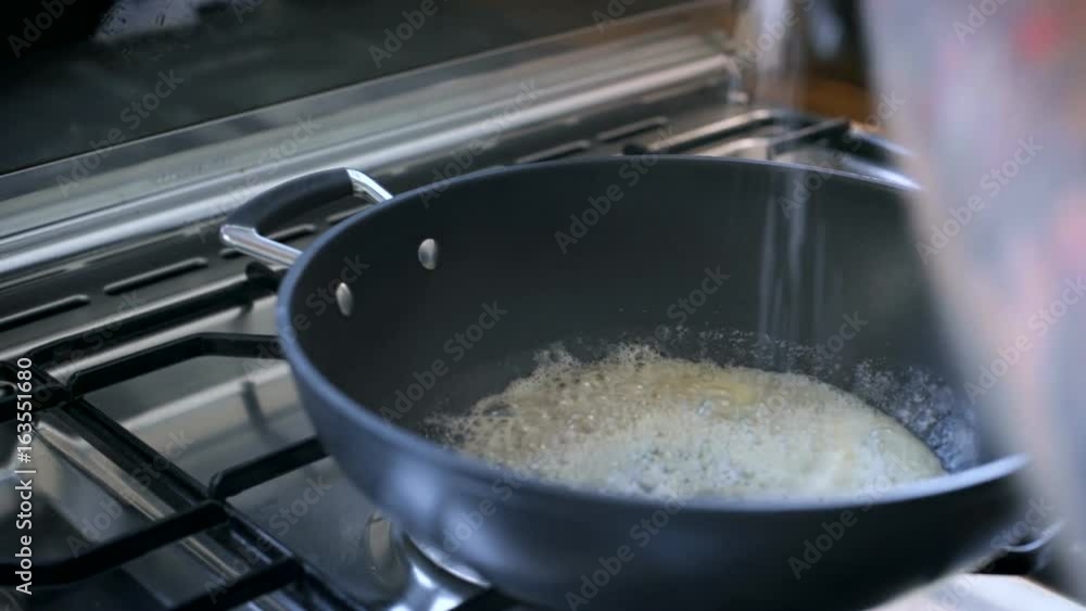 Unconventional chef is stiring and preparing base for sauce inside big pan, melts butter, adds sea salt chunks, grounded black pepper and other spices Unconventional chef is stiring and preparing base for sauce inside big pan, melts butter, adds sea salt chunks, grounded black pepper and other spices