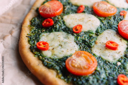 Appetizing pizza with pesto mozzarella and cherry and chili peppers