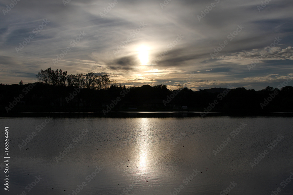 Dark sunset over a lake with dark forest in background