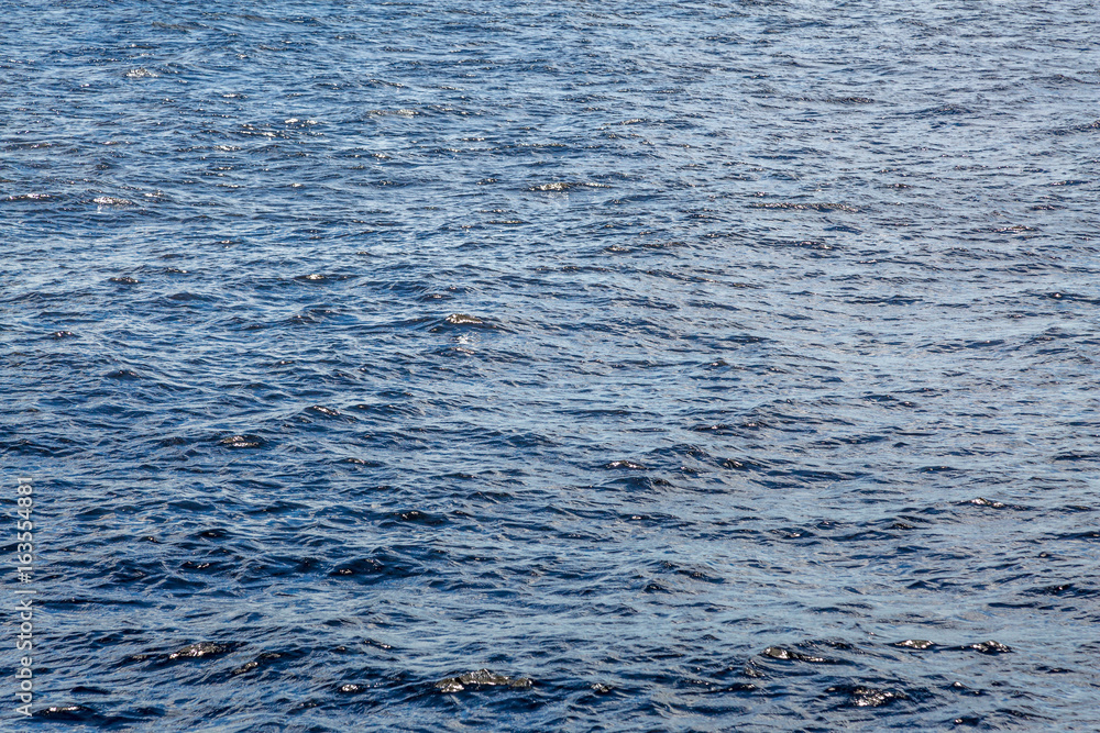 The water surface of the river, sea, lake or ocean. Textured background. The water surface of the river, sea, lake or ocean. Textured background.