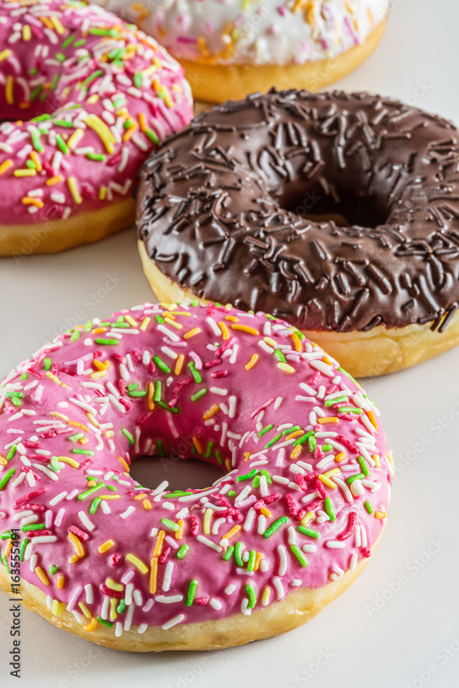 Tasty donuts with colorful sprinkles on light background Tasty donuts with colorful sprinkles on light background