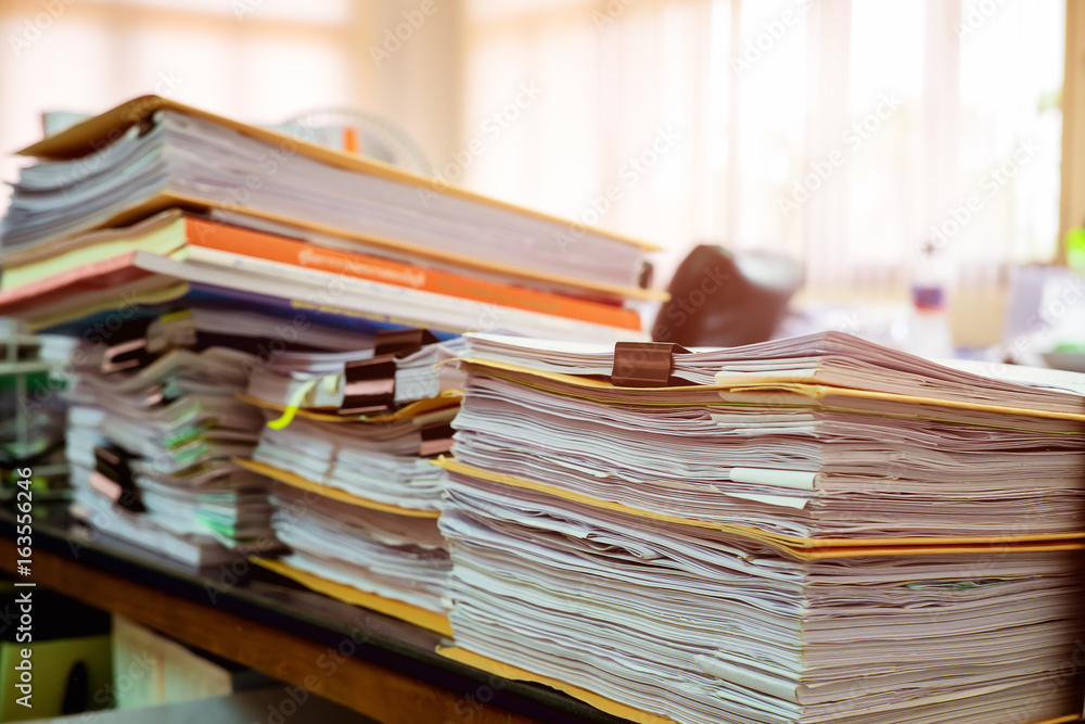 Close up paper stack on the desk related to business functions.Stack of business document files,report paper of accounting and financial with morning light,soft focus Close up paper stack on the desk related to business functions.Stack of business document files,report paper of accounting and financial with morning light,soft focus
