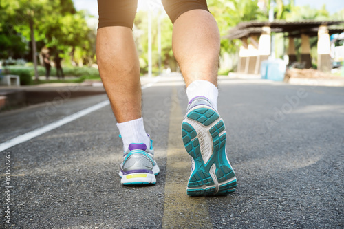 Runner athlete feet running on road. young man in sports clothing running in park