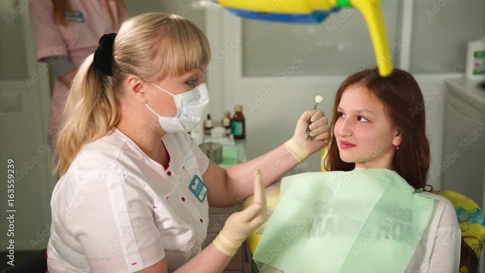 Dentist talking with young patient. Young girl attending dentist. Beautiful blonde female dentist. Conversation between dentist and child. Dentist talking with young patient. Young girl attending dentist. Beautiful blonde female dentist. Conversation between dentist and child.