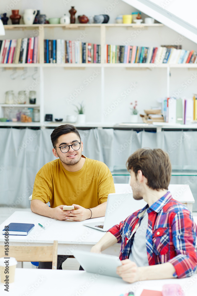 Two young designers consulting at meeting Two young designers consulting at meeting