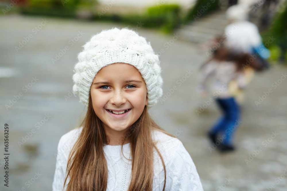 Portrait of pretty teenage girl smiling looking at camera while playing with friends outdoors on warm autumn day Portrait of pretty teenage girl smiling looking at camera while playing with friends outdoors on warm autumn day