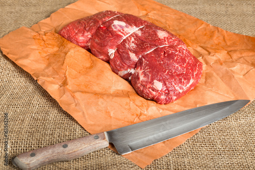 Cut of fresh raw beef on butcher paper with knife